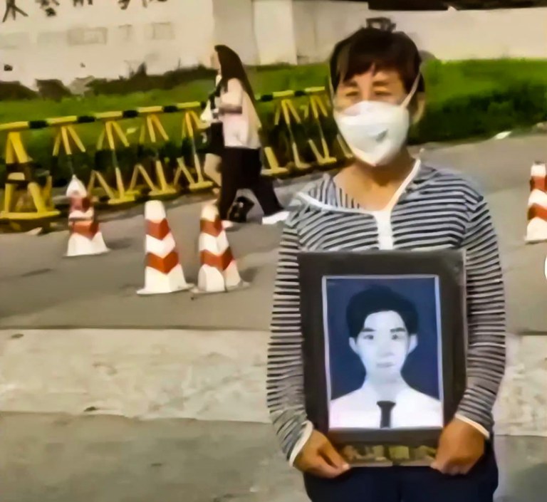 Gao Yan's mother holds a portrait of him at the entrance of Shandong University of Arts. Credit: Network screenshot
