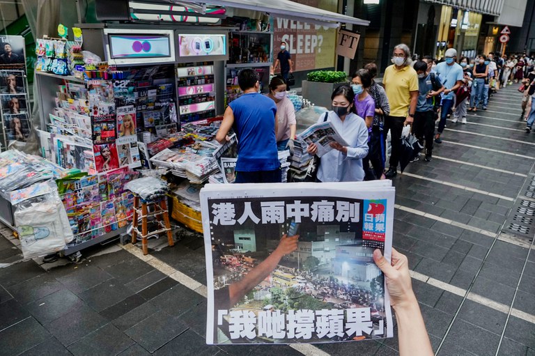 In this June 24, 2021 file photo, a woman takes a photo of the last issue of Apple Daily in front of a newspaper booth where people queue up to buy the publication in Hong Kong. Credit: Associated Press