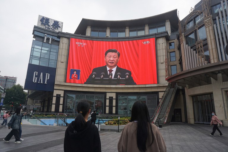 People watch an outdoor screen showing the live speech of Chinese President Xi Jinping during the opening session of the 20th Chinese Communist Party Congress in Hangzhou, China, October 16, 2022. Credit: AFP