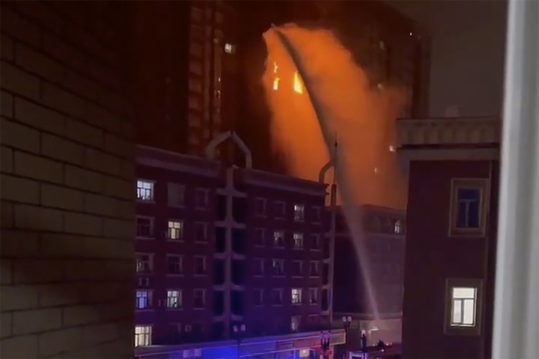 Firefighters spray water on a fire on a residential building in Urumqi in China's Xinjiang region, Nov. 24, 2022. The blaze killed and injured dozens of people. Credit: Associated Press screenshot from video
