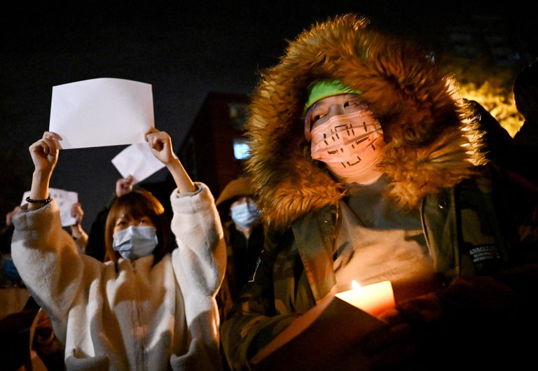 Women protesters march along a street during a rally for the victims of a deadly fire as well as a protest against China's harsh COVID-19 restrictions in Beijing, Nov. 28, 2022. Credit: AFP
