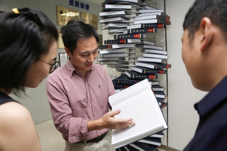 Scientist He Jiankui shows "The Human Genome," a book he edited, at his company Direct Genomics in Shenzhen, Guangdong province, China, in 2016. Credit: Reuters