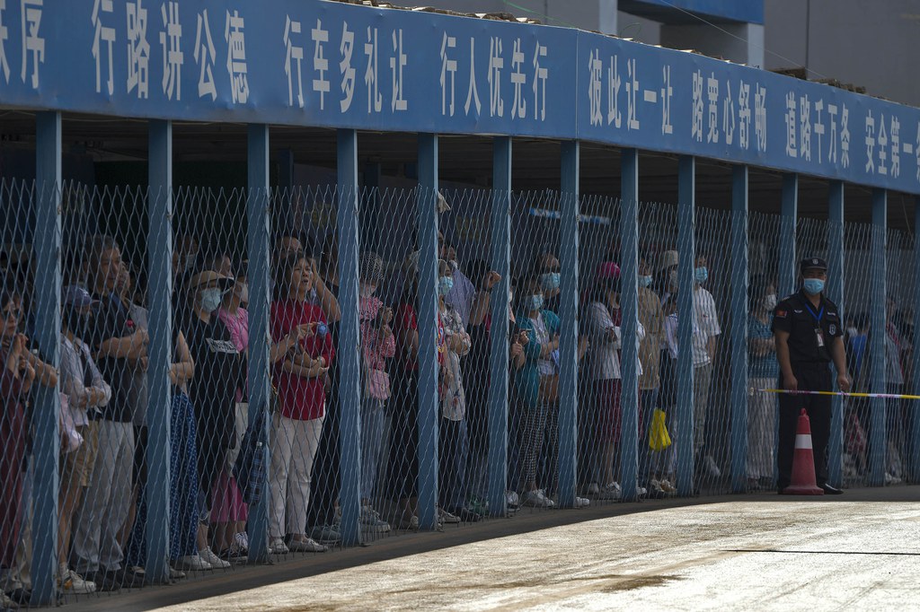 Parents stand and watch as students enter a school to sit for the gaokao exam in Beijing, June 7, 2023. Credit: Andy Wong/AP