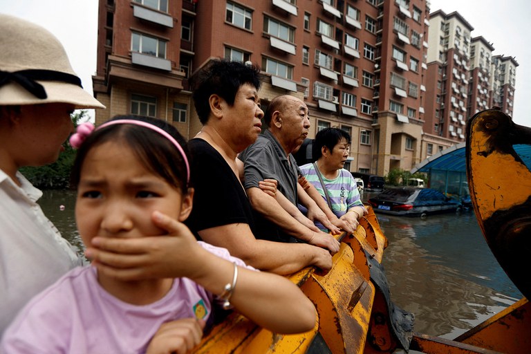 People stand on a front loader as they’re evacuated from a flooded residential compound after flooding brought by remnants of Typhoon Doksuri, in Zhuozhou, Hebei province, China, Aug. 3, 2023. Credit: Tingshu Wang/Reuters