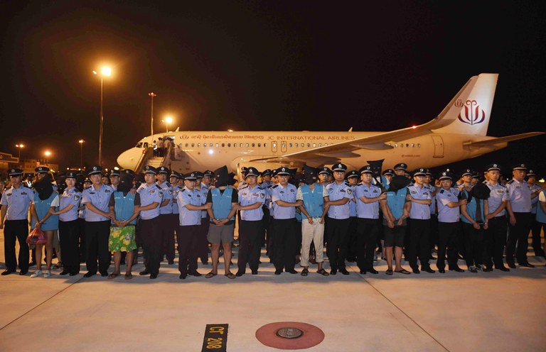 Police officers pose for a photo with suspects of telecom scams as they were brought back to China from Cambodia at Chengdu Shuangliu International Airport in Chengdu, Sichuan Province, China, Aug. 24, 2017. Credit: Wu Guangyu/Xinhua via Getty Images