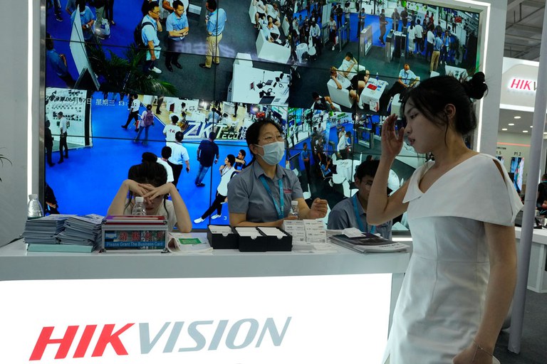 Staffers wait for visitors under a display of CCTV images at the Hikvision booth, a state-owned surveillance equipment manufacturer, during Security China 2023 in Beijing, June 7, 2023. Credit: Ng Han Guan/AP