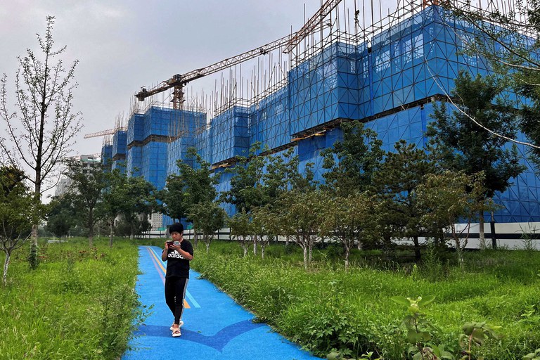 A man walks past a construction site of residential buildings by Chinese developer Country Garden, in Beijing, Aug. 11, 2023. Concerns over China’s real-estate sector have grown to anxiety over the country’s overall economic health and the viability of its investment-led development model. Nowhere have those concerns reverberated more than in Southeast Asia. Credit: Tingshu Wang/Reuters