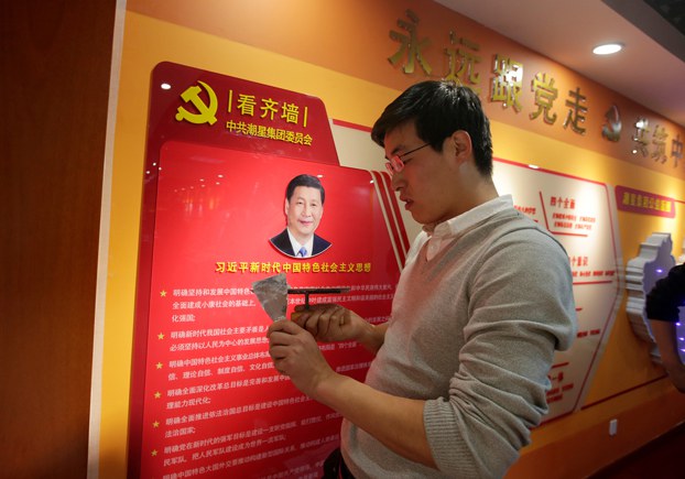 A worker decorates a party activity room next to a wall with the portrait of Chinese president Xi Jinping promoting his socialist thought with Chinese characteristics at Tidal Star Group headquarters in Beijing, Feb. 25, 2019. Credit: Jason Lee/Reuters
