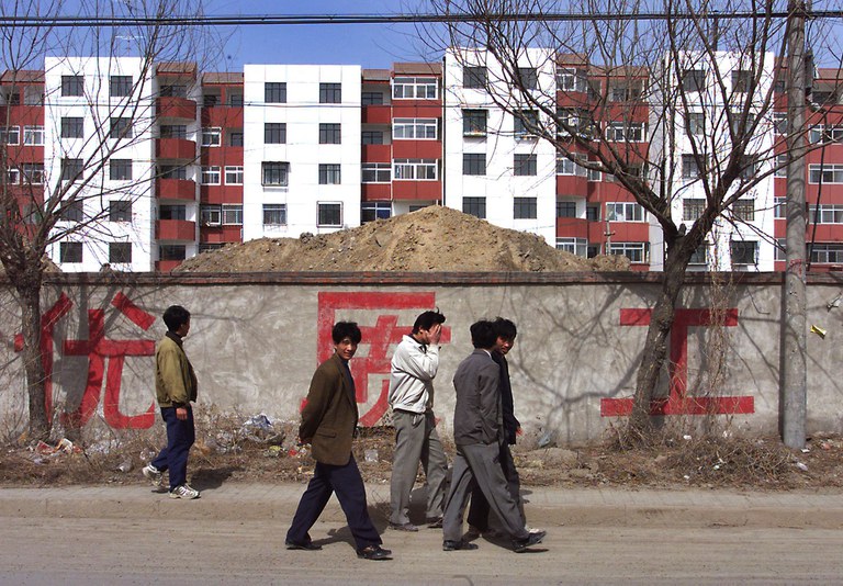 People walk past a newly completed housing project in Beijing in 1999. Li Keqiang pushed for more affordable housing to be built, turning shanty towns into more than 59 million affordable housing units, giving 140 million low income people their first fixed abode.Credit: Goh Chai Hin/AFP