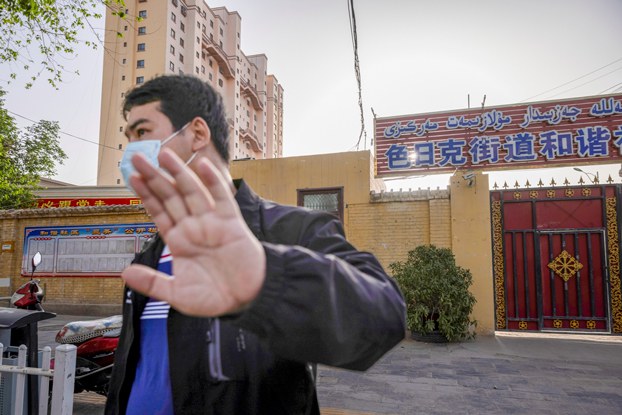 An unidentified man attempts to prevent the photographer from taking pictures outside the site of the Jiaman Mosque in Qira in northwestern China's Xinjiang Uyghur Autonomous Region, April 28, 2021. (Thomas Peter/Reuters)